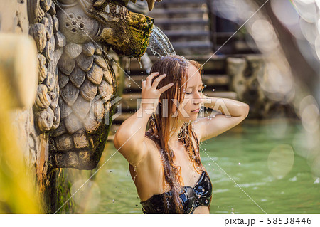 Young woman in hot springs banjar. Thermal water is released from the mouth of statues at a hot Young woman in hot springs banjar. Thermal water is released from the mouth of statues at a hot 58538446