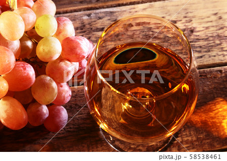 Cognac or Brandy in a glass and fresh grapes, still life in rustic style, vintage wooden background 58538461