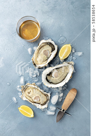 Fresh raw oysters, shot from the top on ice with a glass of white wine and lemon slices Fresh raw oysters, shot from the top on ice with a glass of white wine and lemon slices 58538654