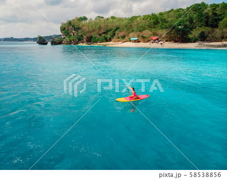 Attractive woman on stand up paddle board on a quiet blue ocean. Sup surfing in tropical sea Attractive woman on stand up paddle board on a quiet blue ocean. Sup surfing in tropical sea 58538856