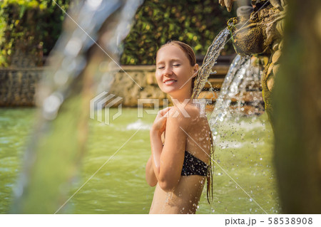 Young woman in hot springs banjar. Thermal water is released from the mouth of statues at a hot Young woman in hot springs banjar. Thermal water is released from the mouth of statues at a hot 58538908