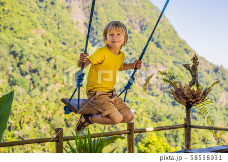 Young boy swinging in the jungle rainforest of Bali island, Indonesia. Swing in the tropics. Swings 58538931