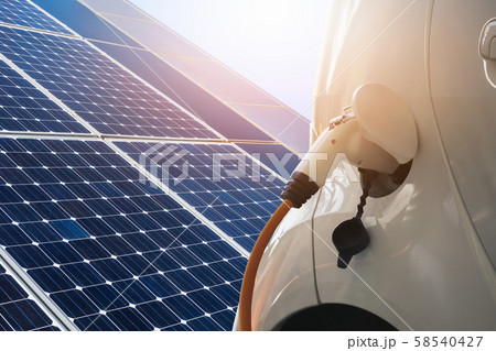 Close up of electric car with a connected charging cable on the background of solar panels and wind turbines - sources of clean renewable energy Close up of electric car with a connected charging cable on the background of solar panels and wind turbines - sources of clean renewable energy 58540427