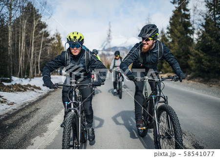 Group of mountain bikers riding on road outdoors in winter. Group of mountain bikers riding on road outdoors in winter. 58541077