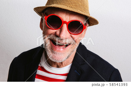 Portrait of a senior man with red sunglasses in a studio, headshot. 58541393