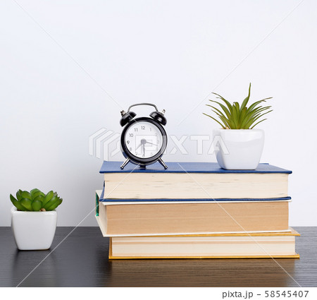 stack books on a black table, on top a ceramic pot 58545407