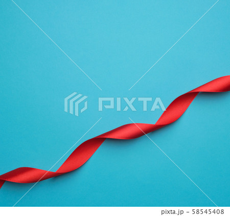 curled red satin ribbon on blue background 58545408