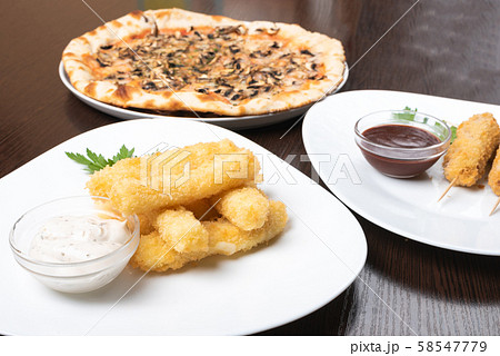 Korndog on skewers, and cheese sticks. Pizza. On the plates. 58547779