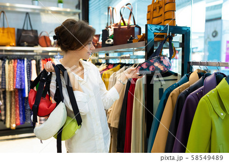 Young woman is holding few waist bags in shop 58549489