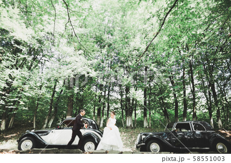 Happy newlywed couple, man and wife kissing near stylish retro car 58551003