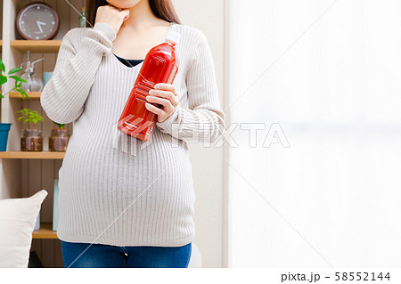 トマトジュースを持って考える妊婦 58552144