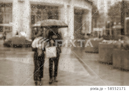 Vintage abstract blurred background. View through glass window with rain drops. People under the Vintage abstract blurred background. View through glass window with rain drops. People under the 58552171