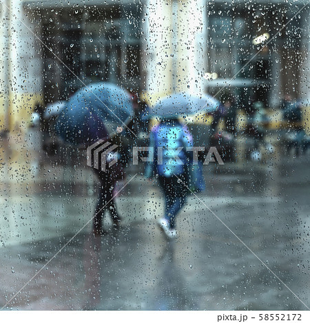 Abstract people under the umbrella, rainy weather, blurred motion. View through glass window with 58552172