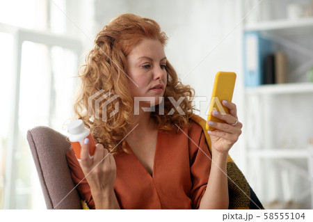 Curly sick woman texting her doctor while feeling dizzy Curly sick woman texting her doctor while feeling dizzy 58555104