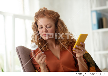 Curly woman holding yellow smartphone after texting doctor Curly woman holding yellow smartphone after texting doctor 58555107