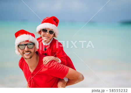 Father and daughter in Santa Hat have fun at tropical beach Father and daughter in Santa Hat have fun at tropical beach 58555232