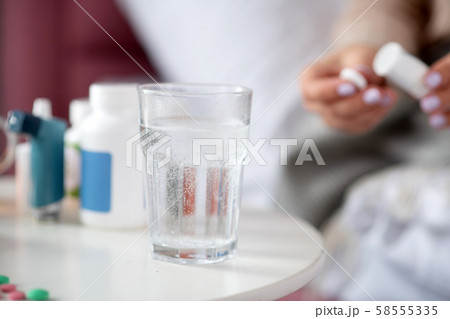 Close up of pill dissolving in glass of water standing on table 58555335