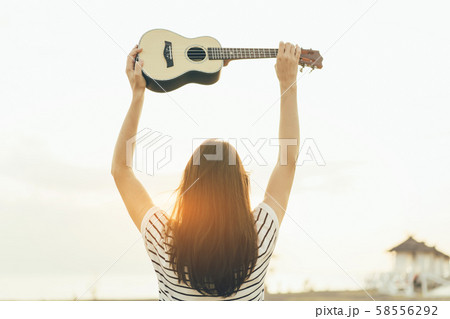 young woman with ukulele view from the back 58556292