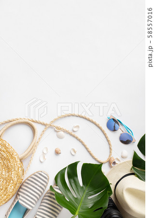 Straw hat, camera, bag, summer shoes, sunglasses, shells and tropical leaves over white background 58557016