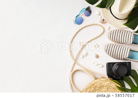 Straw hat, camera, bag, summer shoes, sunglasses, shells and tropical leaves over white background Straw hat, camera, bag, summer shoes, sunglasses, shells and tropical leaves over white background 58557017