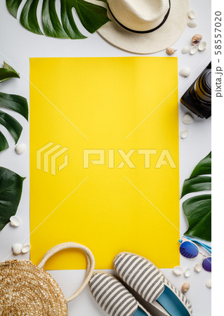 Straw hat, camera, bag, summer shoes, sunglasses, shells and tropical leaves over white and yellow 58557020