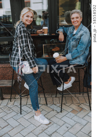Women with cups of coffee sitting outdoors 58558502