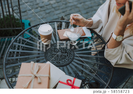 Female with a cellphone enjoying dessert outdoors 58558723