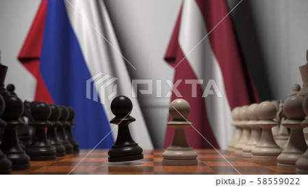 Flags of Russia and Latvia behind pawns on the chessboard. Chess game or political rivalry related 58559022