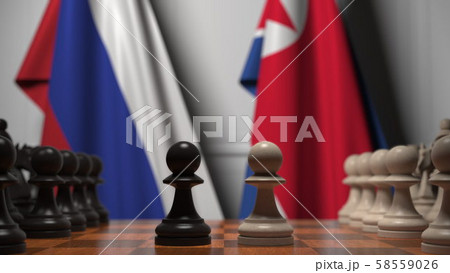 Flags of Russia and North Korea behind pawns on the chessboard. Chess game or political rivalry Flags of Russia and North Korea behind pawns on the chessboard. Chess game or political rivalry 58559026