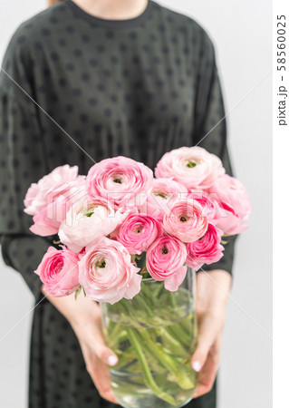 Multicolor pink buttercup, Ranunculus in a vase in woman hand. the work of the florist at a flower Multicolor pink buttercup, Ranunculus in a vase in woman hand. the work of the florist at a flower 58560025