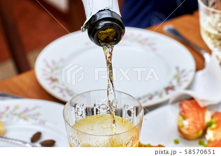 Pouring champagne into the glass from the bottle, 58570651