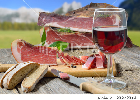 Typical South Tyrolean bacon snack with rye bread lying in front of alpine pastures of the alps Typical South Tyrolean bacon snack with rye bread lying in front of alpine pastures of the alps 58570833