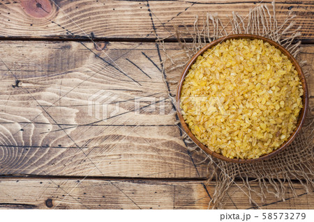 Traditional Turkish dry raw bulgur cereal in a wooden bowl. 58573279