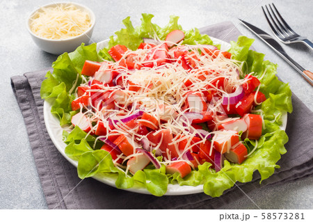 A delicious salad of crab sticks cherry tomatoes and grated cheese with onions in a serving plate. Copy space 58573281