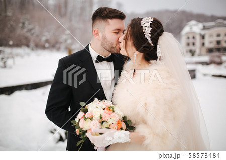 Newlyweds in witer park are walking around. Handsome groom and beautiful bride surrounded by snow 58573484