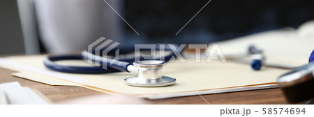 Medical stethoscope head lying at paper document on table 58574694