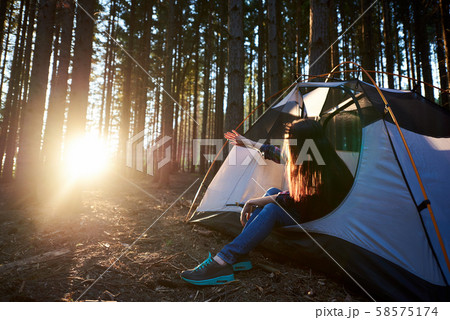 Tourist woman sitting in white tent, enjoying sunrise 58575174
