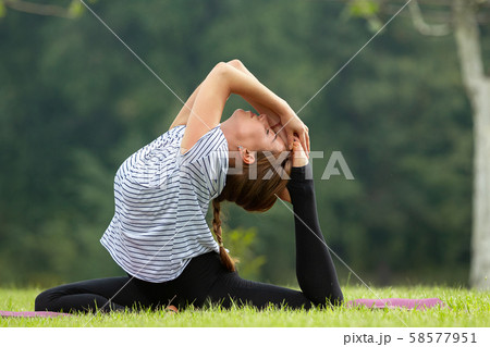 Young beautiful woman doing yoga exercise in green park. Healthy lifestyle and fitness concept. Young beautiful woman doing yoga exercise in green park. Healthy lifestyle and fitness concept. 58577951