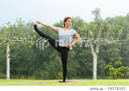 Young beautiful woman doing yoga exercise in green park. Healthy lifestyle and fitness concept. 58578105