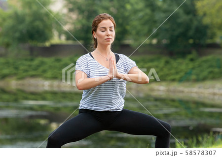 Young beautiful woman doing yoga exercise in green park. Healthy lifestyle and fitness concept. 58578307