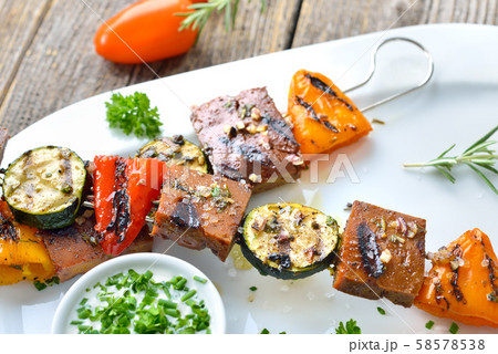 Vegan meal: Grilled skewers with mixed vegetables and seitan served with a herb soy sauce 58578538
