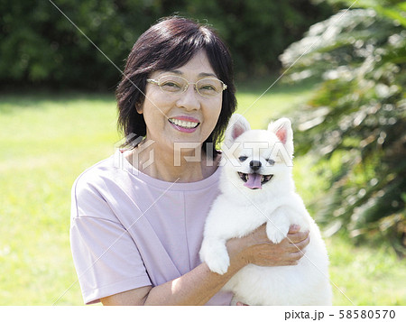 犬を抱く笑顔のシニア女性 犬を抱く笑顔のシニア女性 58580570