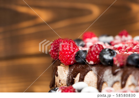A close-up view of vegan chocolate cake covered with raspberries and blueberries, frozen in the A close-up view of vegan chocolate cake covered with raspberries and blueberries, frozen in the 58580830
