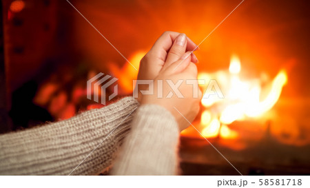 Closeup photo of young wooman feeling cold sitting by the burning fire at house and rubbing freezing 58581718