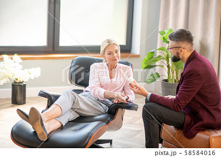 Woman sitting on comfy armchair and listening to doctor advice Woman sitting on comfy armchair and listening to doctor advice 58584016