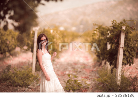 Smiling woman in white dress standing in vineyard 58586136