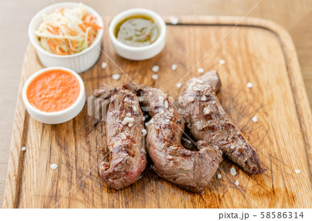 Lamb tenderloin with Pickled cabbage and two sauces. Serving on a wooden Board. Barbecue restaurant Lamb tenderloin with Pickled cabbage and two sauces. Serving on a wooden Board. Barbecue restaurant 58586314