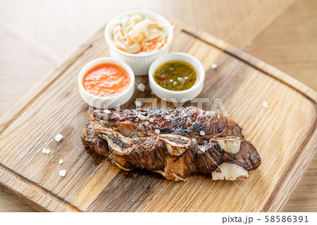 Beef meat cut according to the Argentine style, called asado. with Pickled cabbage and two sauces 58586391