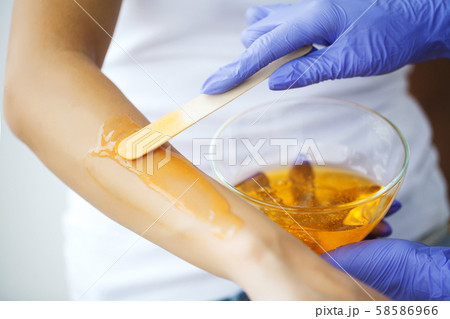 Master does epilation of hands with help of sugar paste hot wax in salon beauty. 58586966