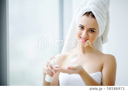 Perfect young woman applying facial cream in bathroom 58586971